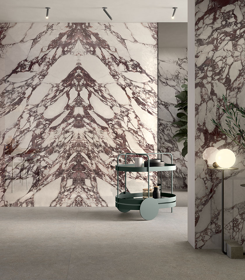 Contemporary interior with large marble-effect surfaces featuring burgundy veining, paired with neutral flooring and designer furnishings.