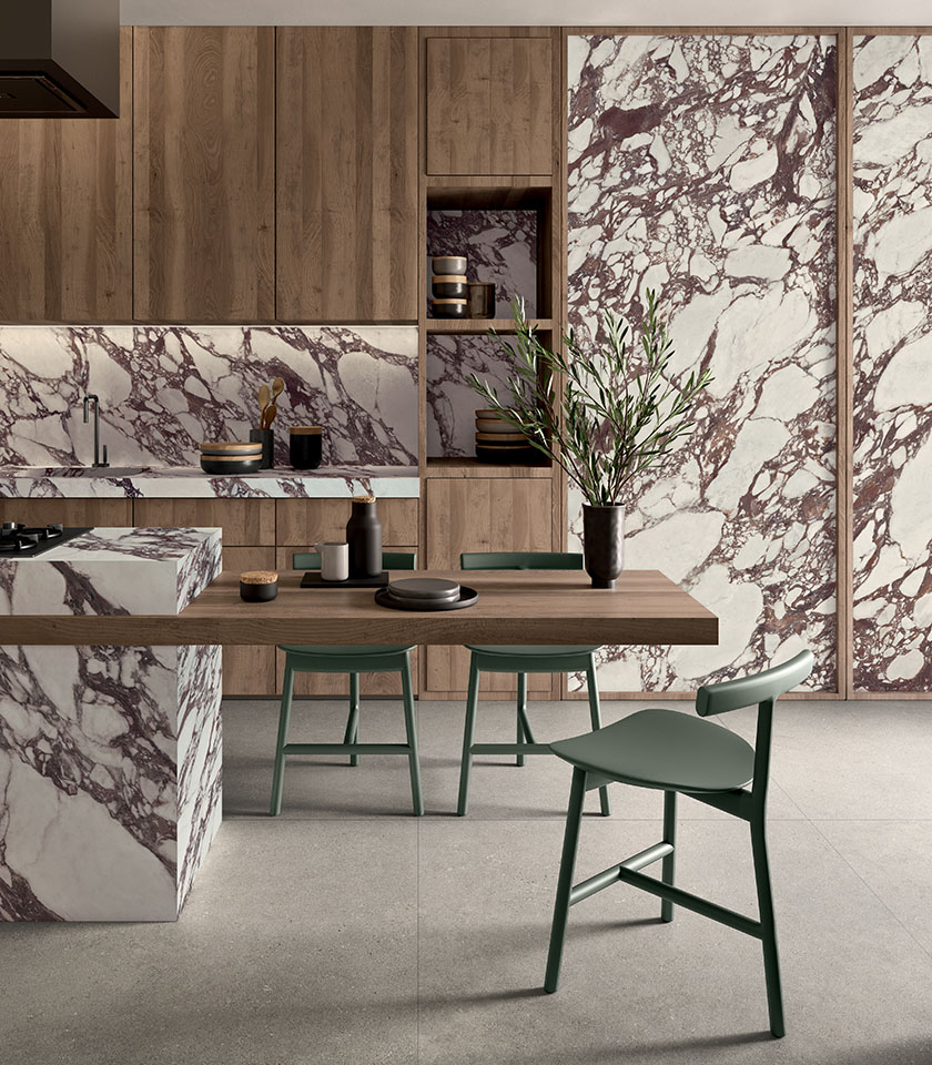 Modern kitchen with bold marble-effect surfaces, natural wood and green details.