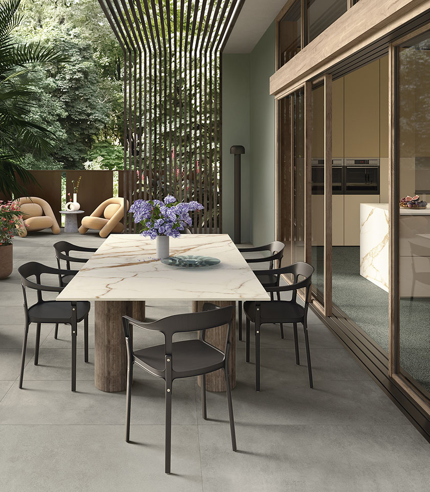 Contemporary terrace with porcelain stoneware flooring, designer furniture, a large marble-effect table and seamless continuity between indoor and outdoor spaces.