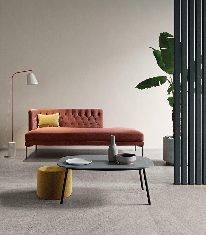Minimal chic living room with grey stone-effect flooring, a terracotta chaise longue, essential furnishings and warm contemporary design accents.
