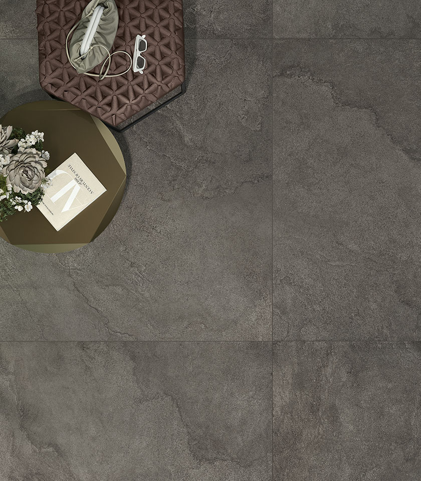 Large-format dark stone-effect porcelain stoneware flooring with contemporary side tables and decorative details.